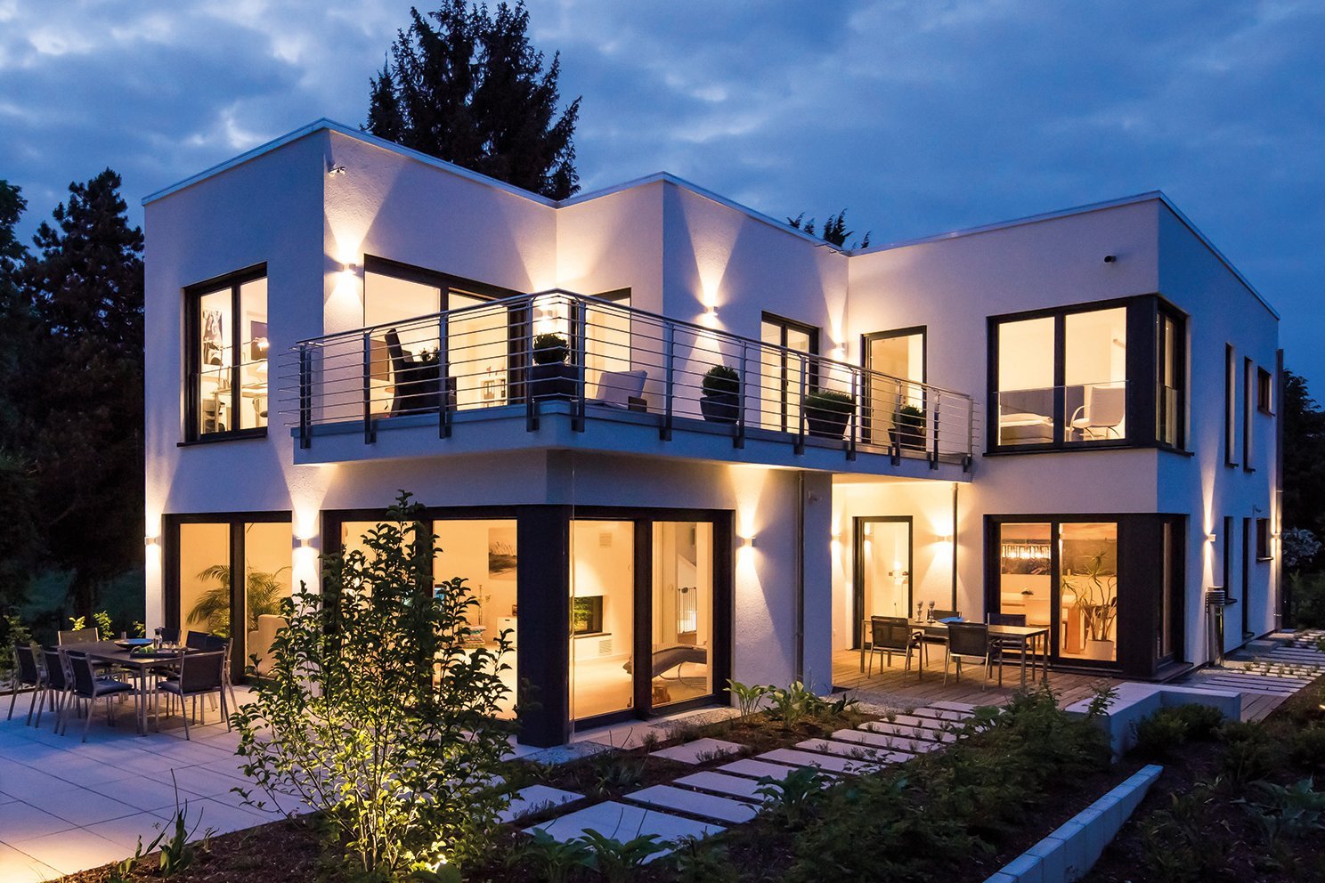 Flachdachhaus mit viel Glas und Balkon und Flachdach in der Nachtansicht